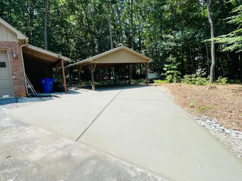 Concrete driveway pad by a carport